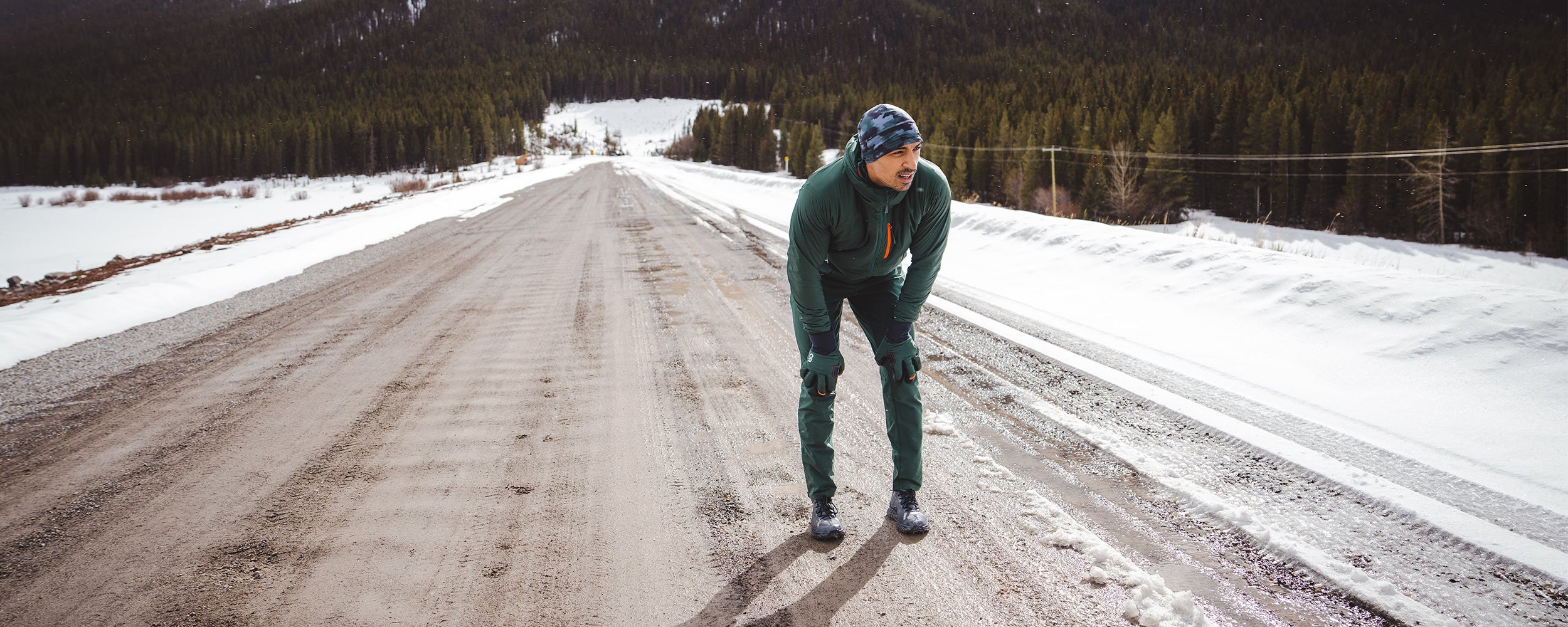A runner takes a break along a snow covered road during winter.