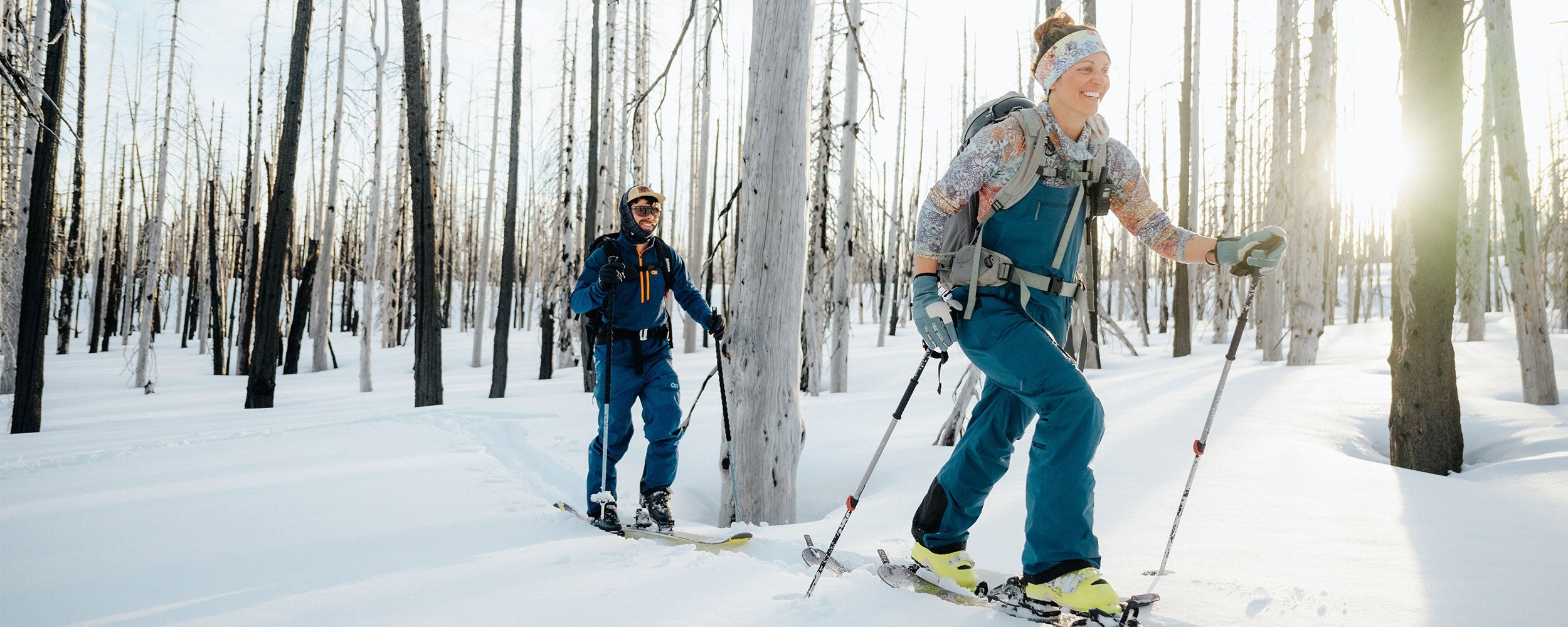 A woman and a man wear Outdoor Research base layers while out on a ski tour.