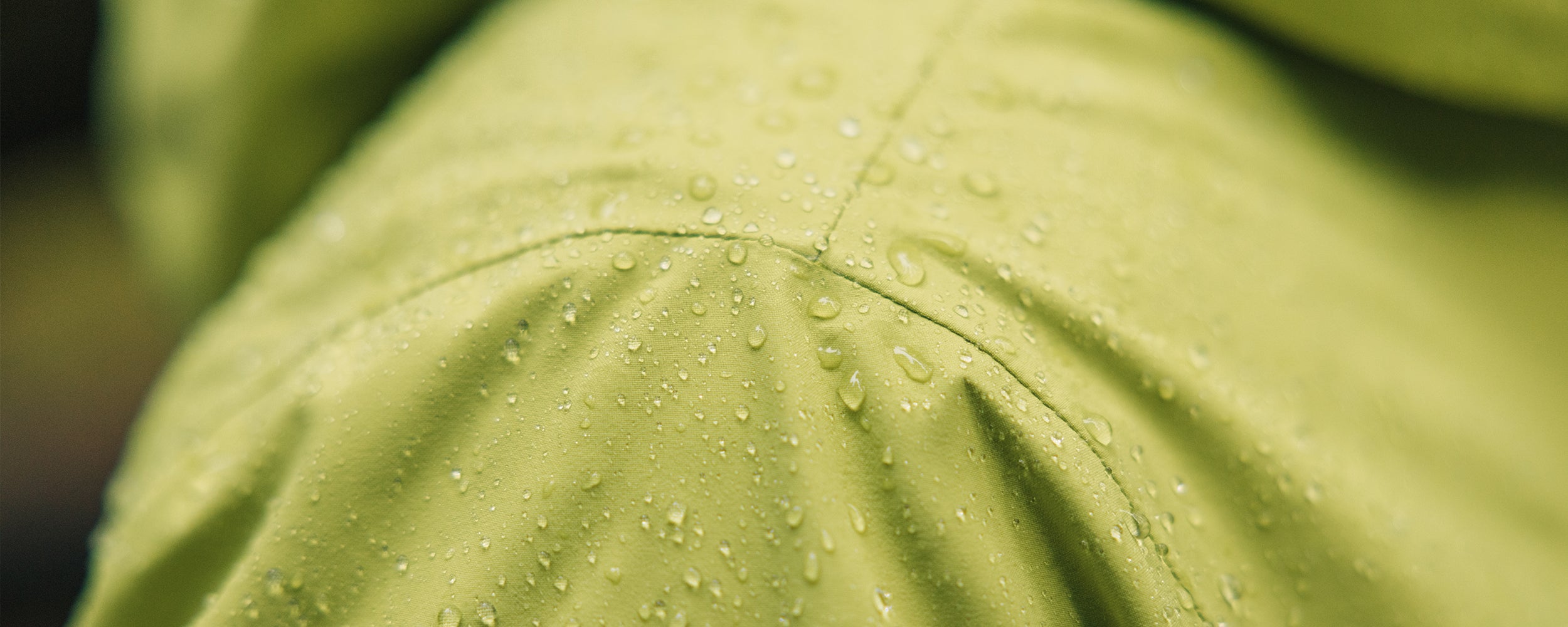 Rain Drops collect on the shoulder of a man wearing the Outdoor Research Foray 3L Jacket in Willow/Green.