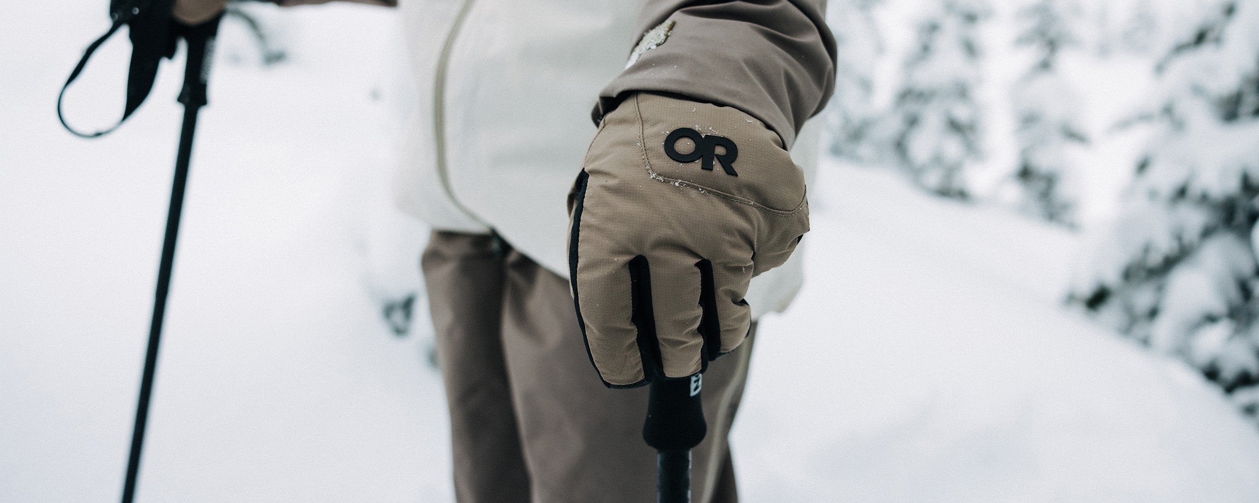 A skier holds their ski poles wearing the Outdoor Research Women's Revolution Undercuff GORE-TEX Gloves in Sable.