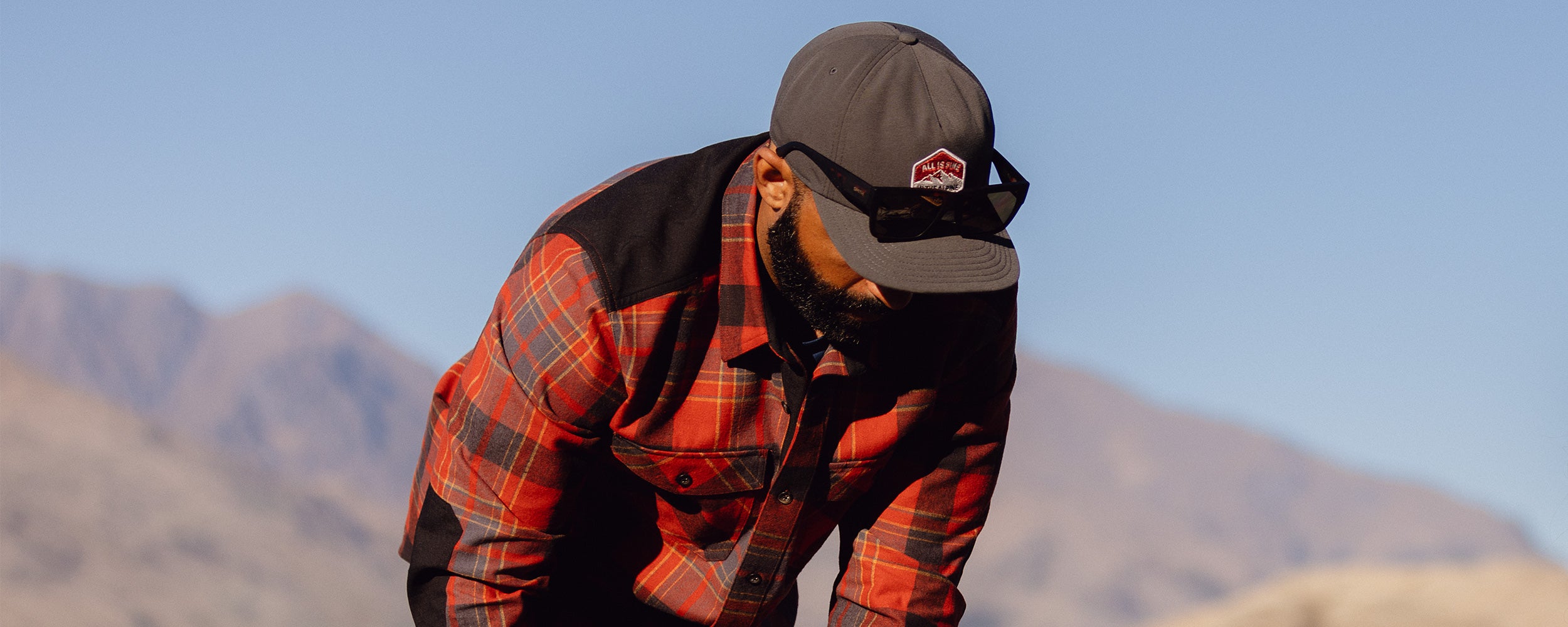 A man wears the Wallingford Flannel Shirt Jacket in Jupiter Plaid while out on a hike.