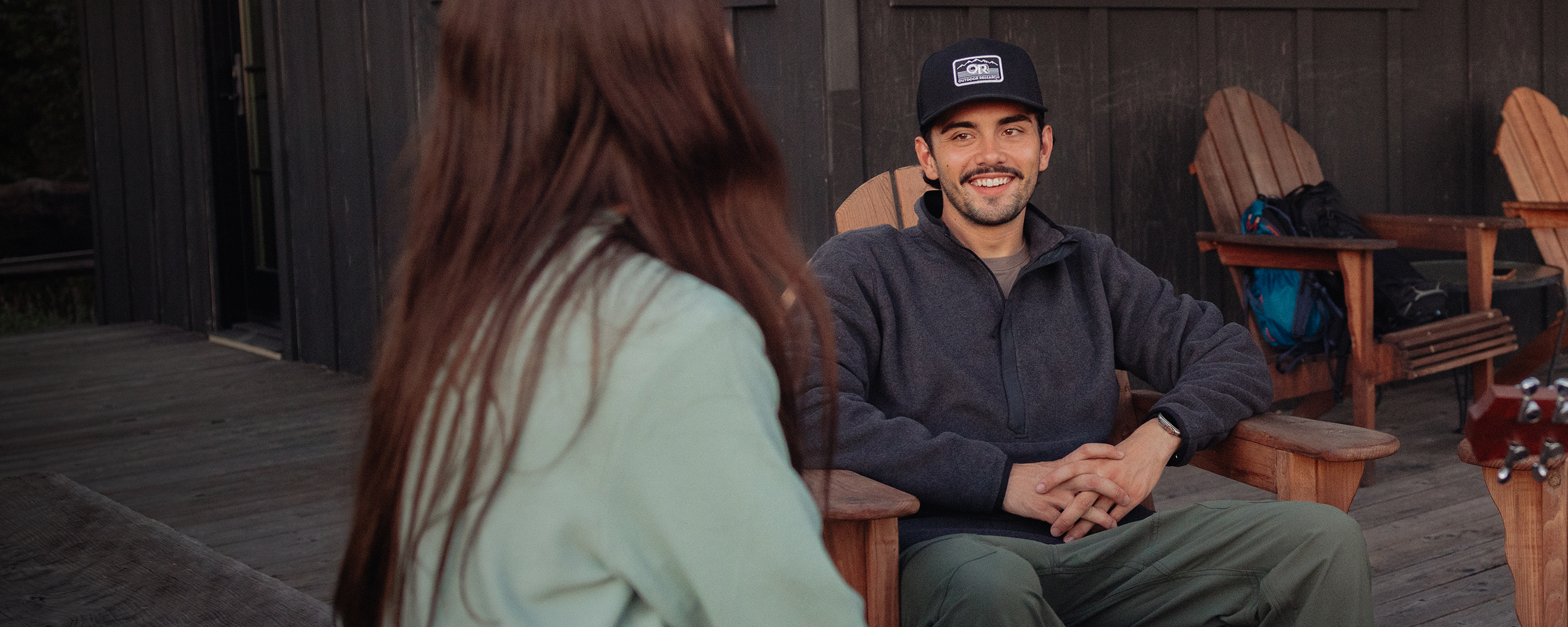 A man pulls up the zipper of his Outdoor Research Men's Trail Mix XT Fleece Jacket Dark Olive while out for a hike with a friend.