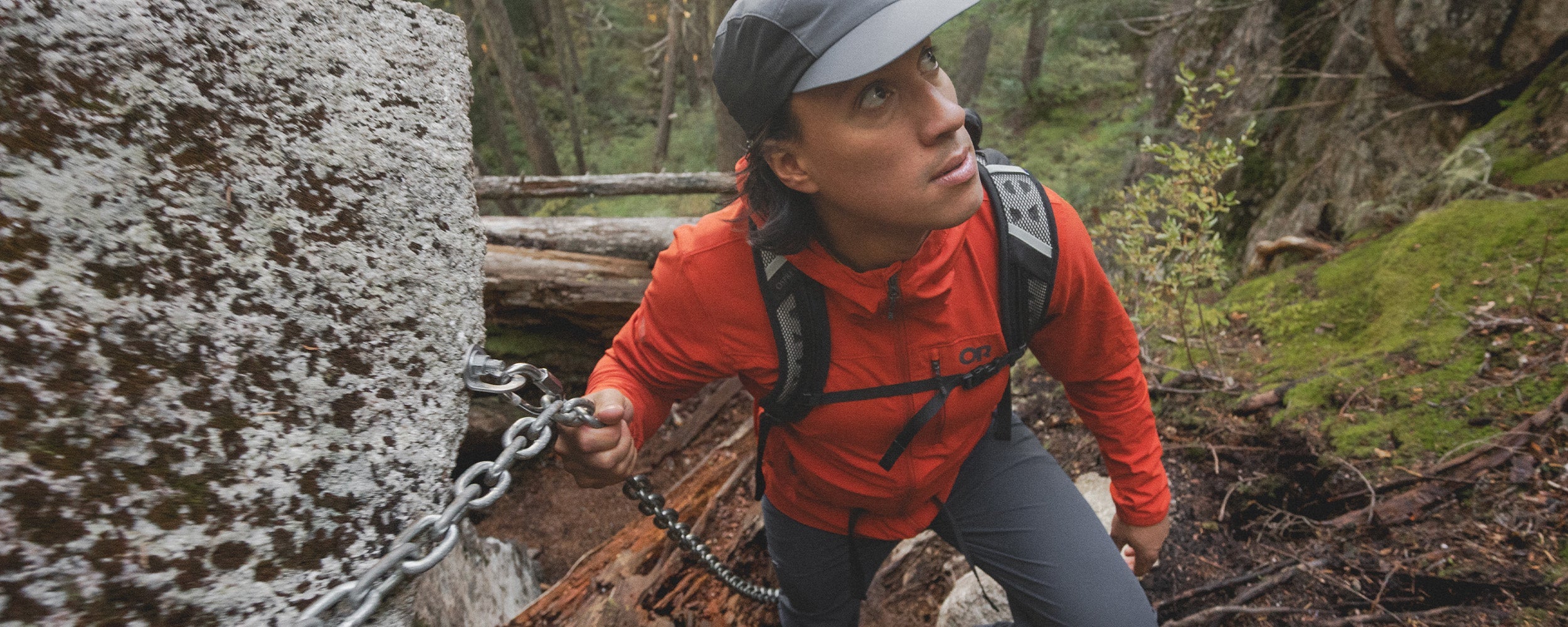 Man crouches on a branch of a tree he climbed while wearing Outdoor Research Ferrosi Pants in Dark Navy.