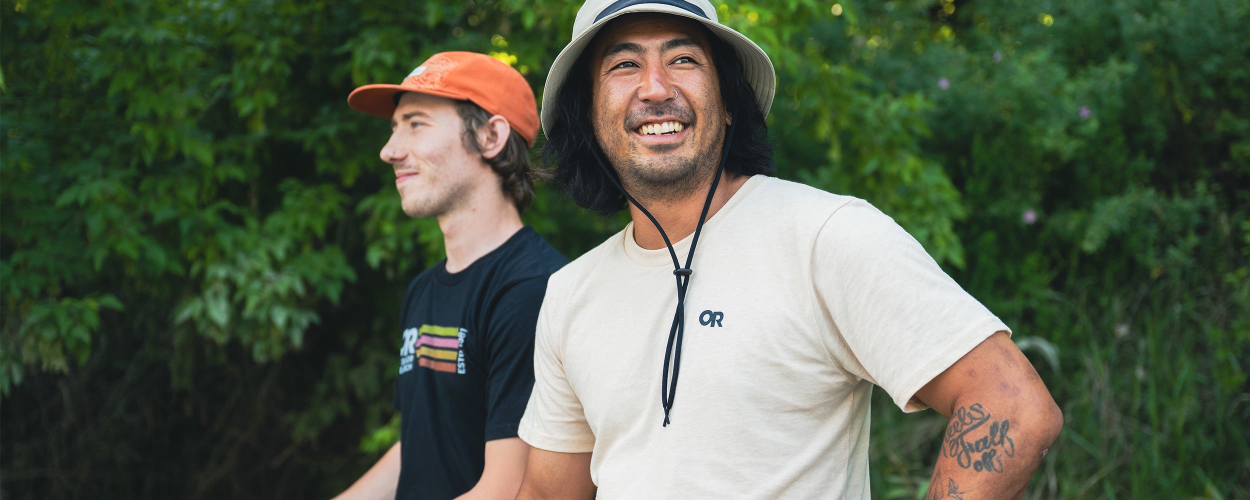 Close up of Outdoor Research athletes Damon Iwanaga and Micah Evangelista smiling while wearing Outdoor Research logo t-shirts and hats.