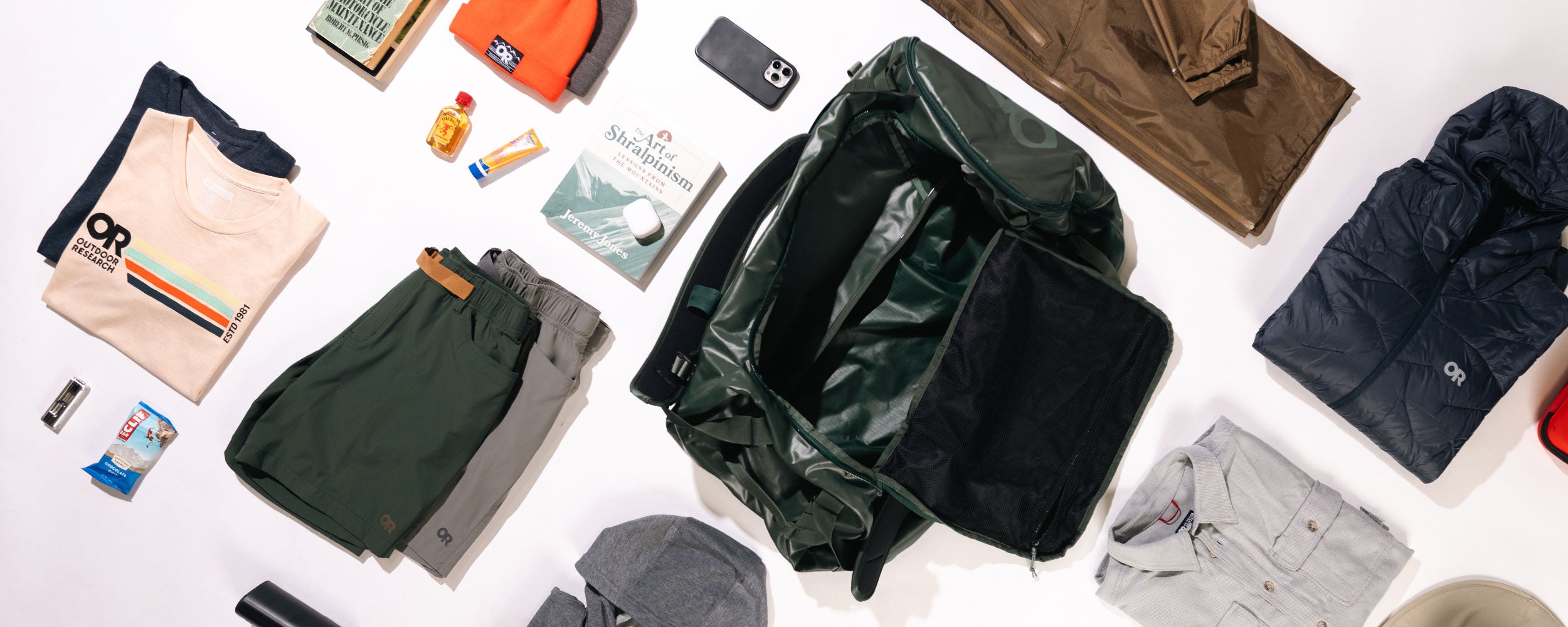 Overhead view of the contents of a duffel bag with clothes and gear all around.