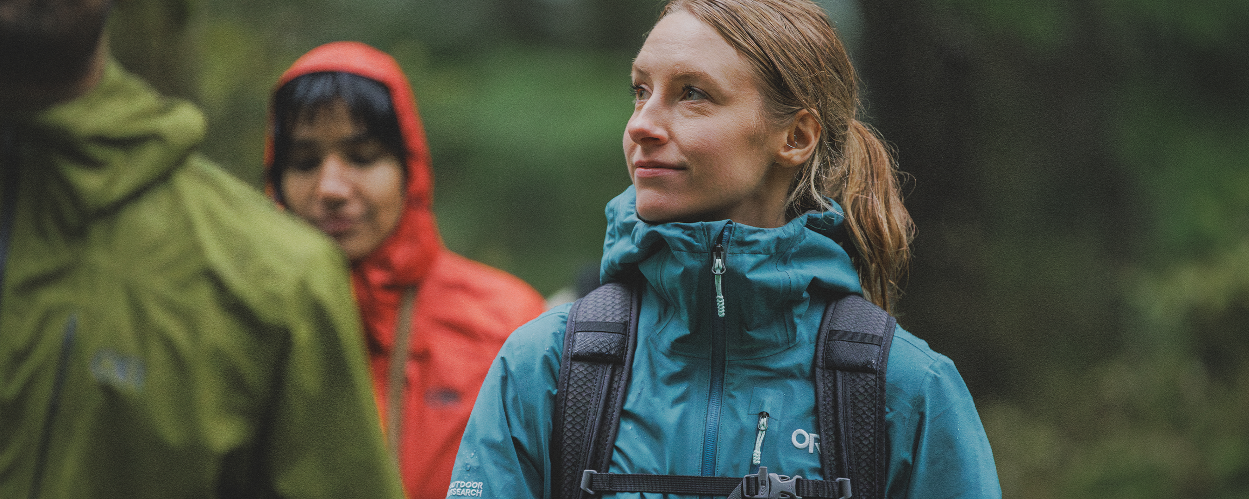 Female walking with two others wearing Outdoor Research Women's Aspire 3L Jacket Mallard. 