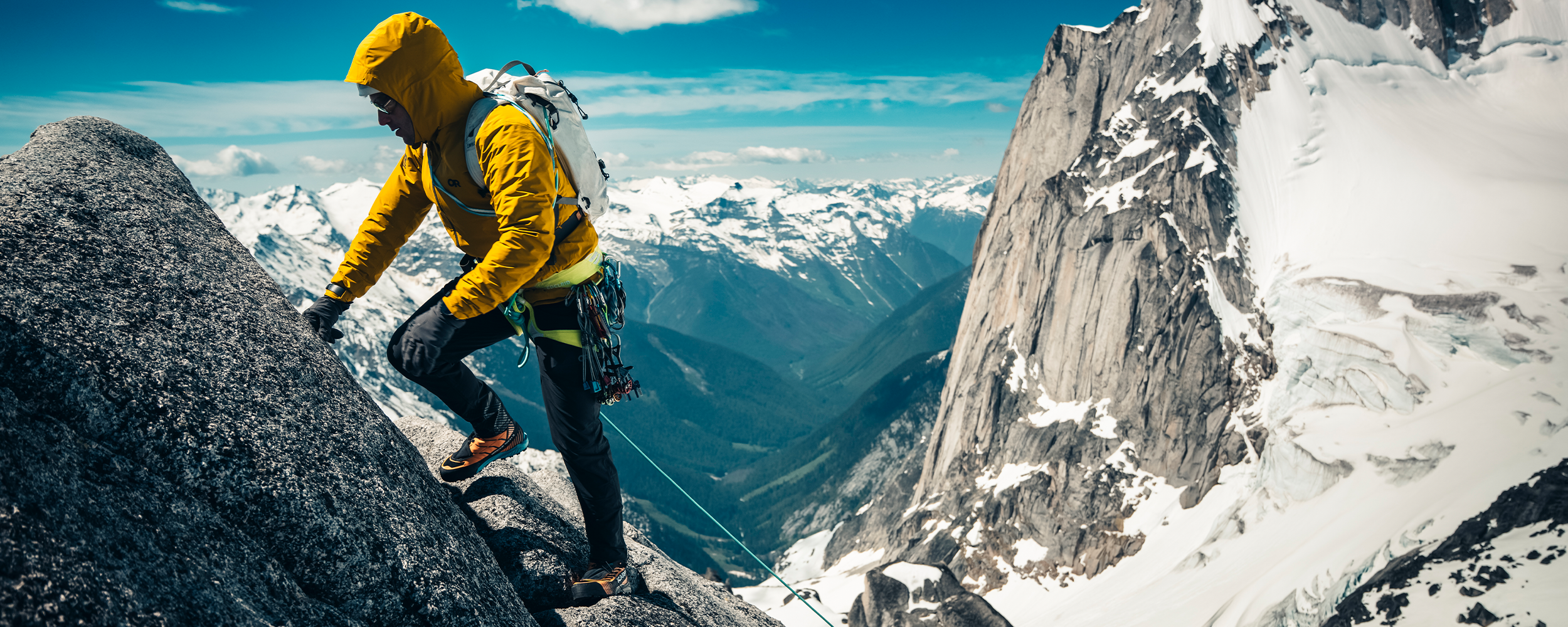 Three people climbing up a rocky mountain wearing Outdoor Research Men's Skychaser Jacket Amber. 