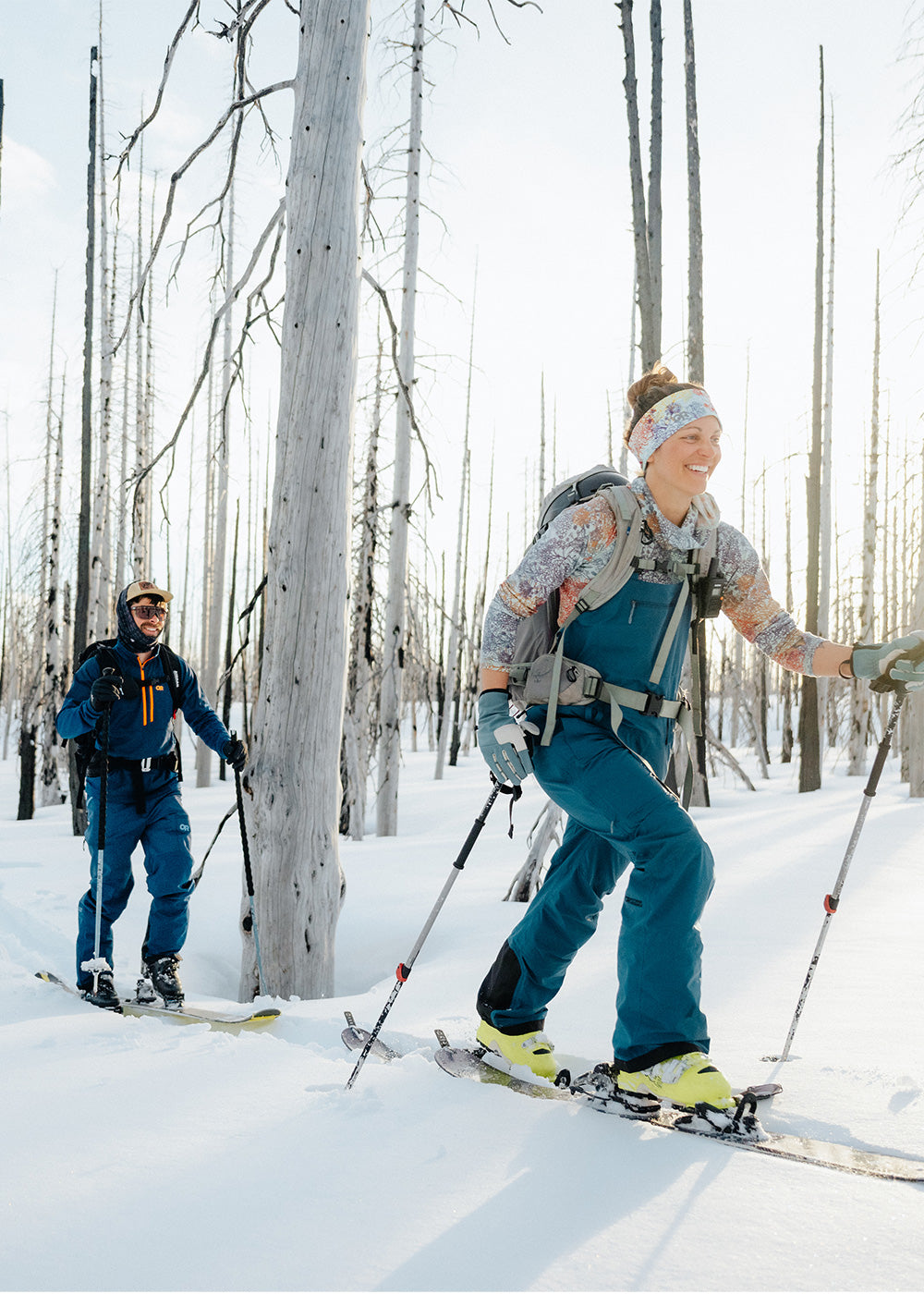 A woman and a man wear Outdoor Research base layers while out on a ski tour.