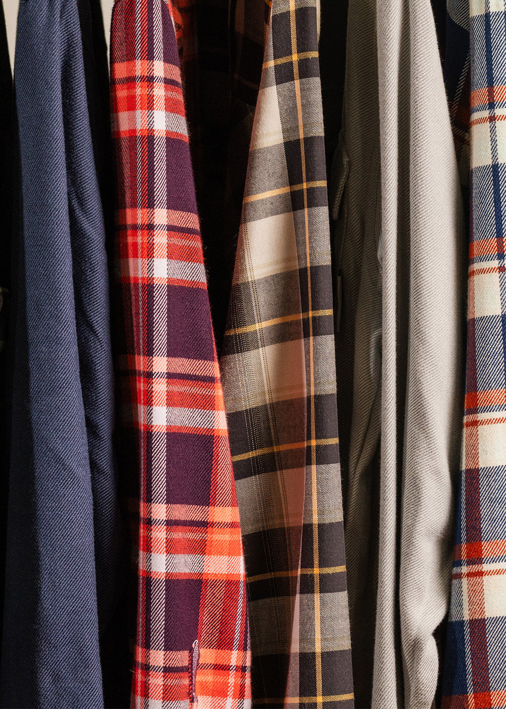 Close up of a variety of Outdoor Research flannel shirts hanging on a rack.