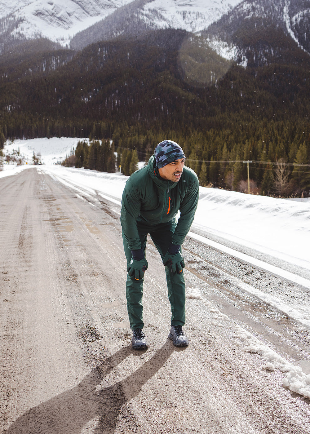 A runner takes a break along a snow covered road during winter.