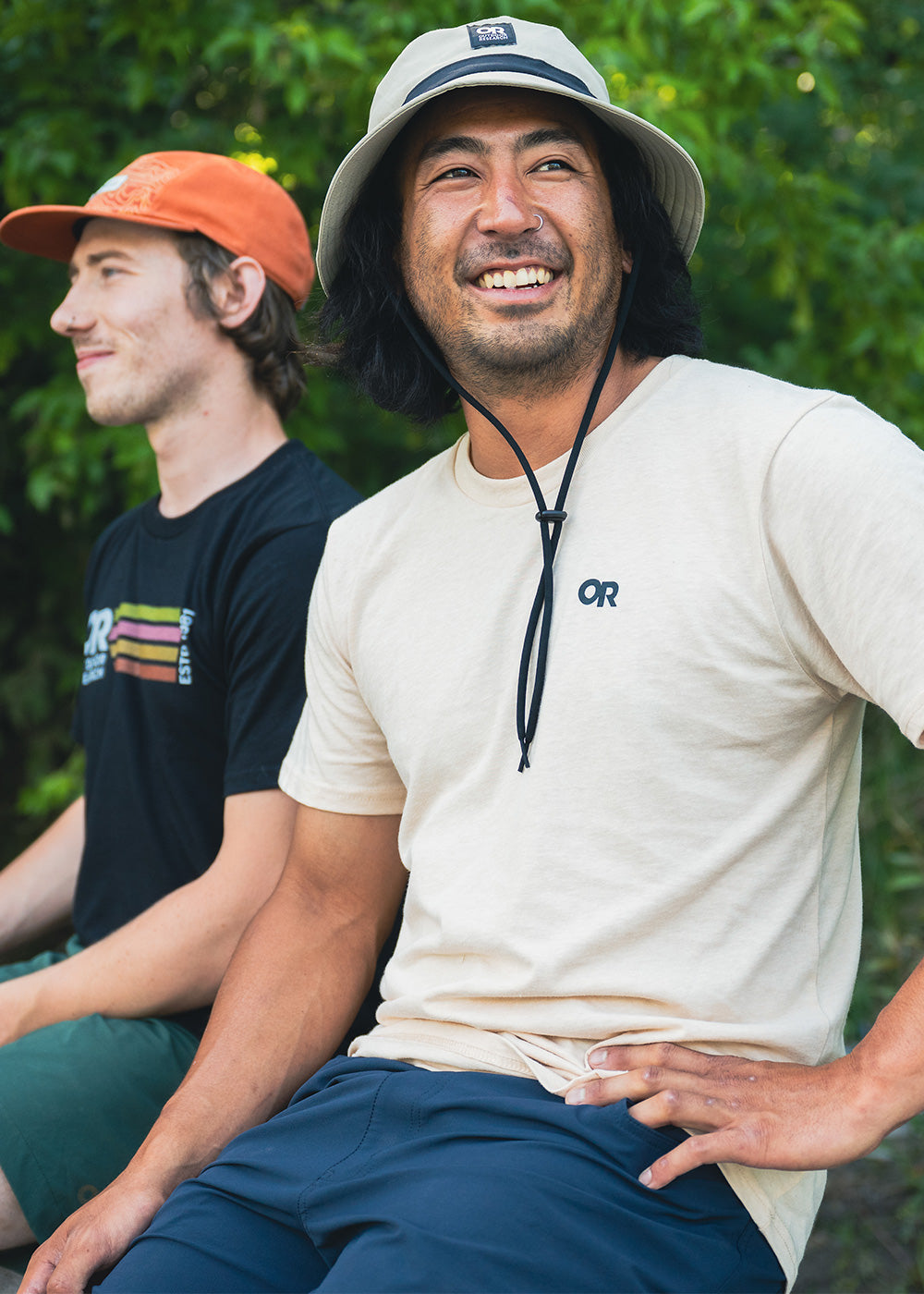 Close up of Outdoor Research athletes Damon Iwanaga and Micah Evangelista smiling while wearing Outdoor Research logo t-shirts and hats.
