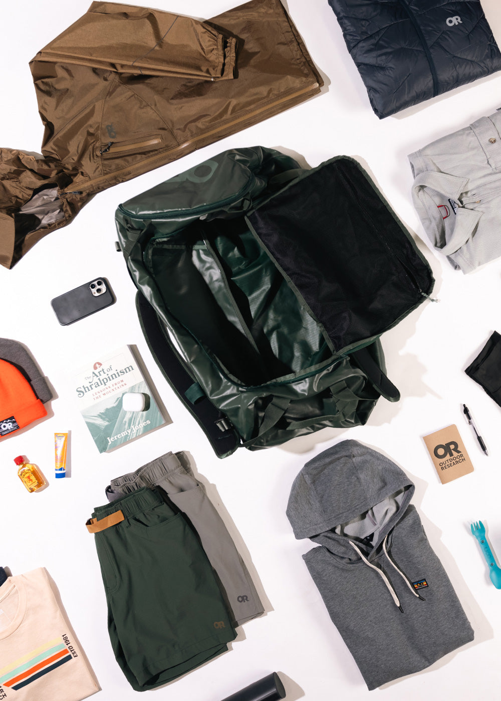 Overhead view of the contents of a duffel bag with clothes and gear all around.