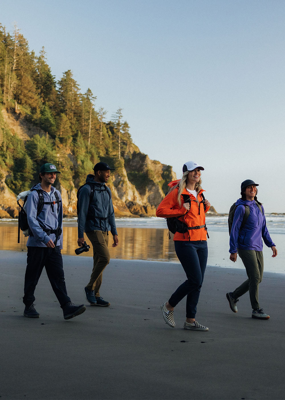 Group of friends stroll along the beach wearing Outdoor Research Outerwear.