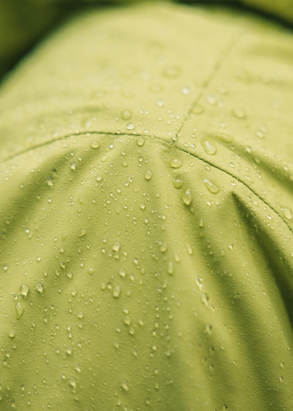 Rain Drops collect on the shoulder of a man wearing the Outdoor Research Foray 3L Jacket in Willow/Green.