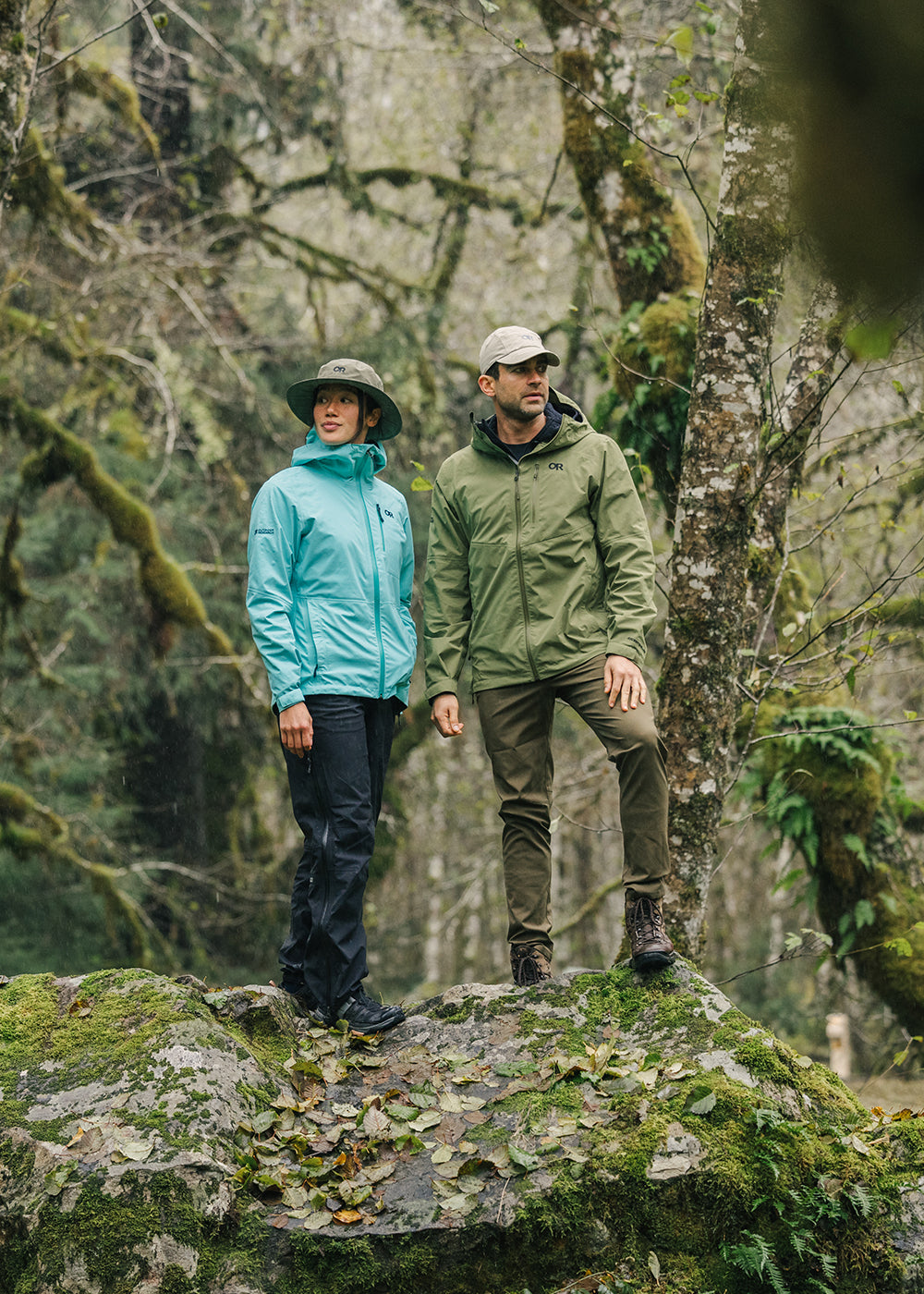 Two friends wearing Outdoor Research outerwear stand on top on a rock during a hike.