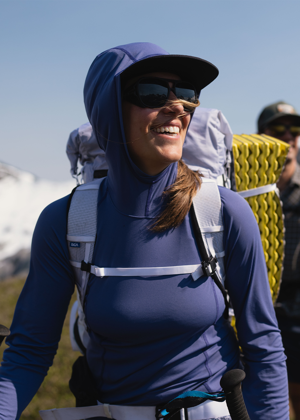 A woman smiles while putting skins on her skis while out on a ski tour.