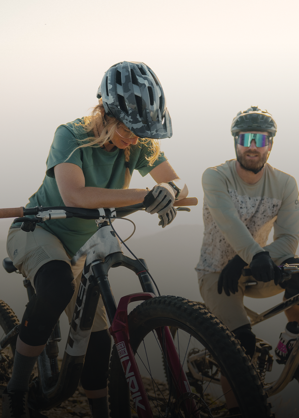 Two people on their bikes at the top of the mountain wearing Outdoor Research Freewheel MTB sportswear. 