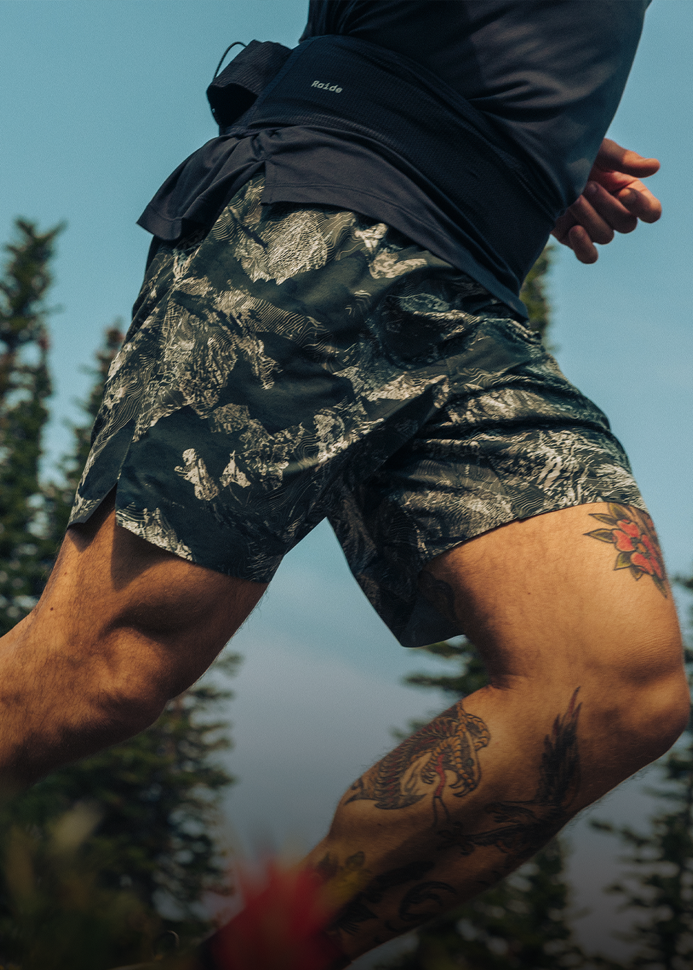Two friends stride through a dry field under the sun wearing Outdoor Research Sportswear. 
