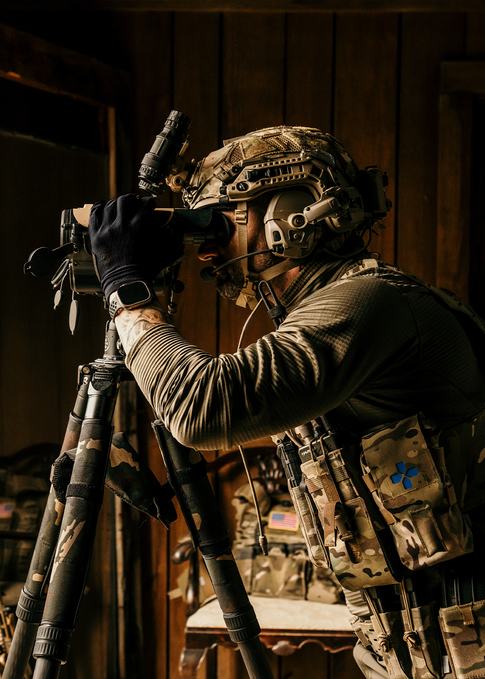 A man wearing alpine camouflaged tactical gear skis through snow while holding tactical equipment.